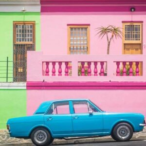 A Blue Car beside Colorful Buildings - Image